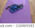 Fabric blue leg weights lie on a yoga mat. Sport equipment. Purple yoga mat. 110465583