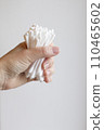 Cotton swabs are held in the hand. A woman's hand holds a lot of cotton swabs in her hand on a white background. 110465602