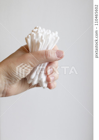 Cotton swabs are held in the hand. A woman's hand holds a lot of cotton swabs in her hand on a white background. Cotton swabs are held in the hand. A woman's hand holds a lot of cotton swabs in her hand on a white background. 110465602