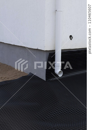 Black waterproofing membrane around the foundation of the house. Construction of the blind area of the house. Reliable protection of the foundation from moisture. Black waterproofing membrane around the foundation of the house. Construction of the blind area of the house. Reliable protection of the foundation from moisture. 110465607