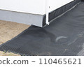 Laying a black waterproofing membrane around the foundation of a house. Construction of the blind area of the house. Reliable protection of the foundation from moisture. White pipe for draining 110465621