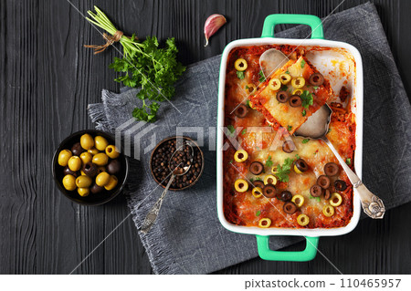 lasagna with olive rings in green baking dish 110465957