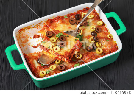 lasagna with olive rings in green baking dish 110465958