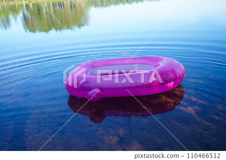 A pink children's swimming circle on the water of a calm lake. 110466512