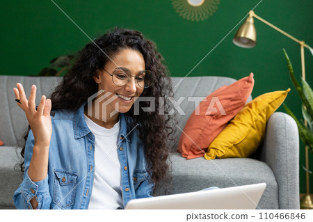 Close-up of joyful woman studying at home, watching video tutorial course, smiling contentedly sitting on sofa in living room, talking with teacher mentor using video call on laptop. 110466846