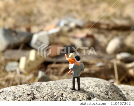 An elderly doll holding a child stands on a rock overlooking the rubble An elderly doll holding a child stands on a rock overlooking the rubble 110467262