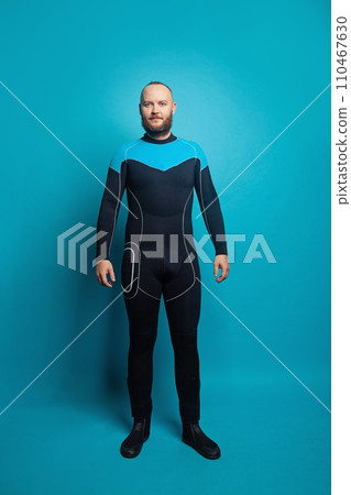 Happy man scuba diver standing on blue background 110467630