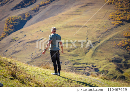 A man stands on a mountain near a cliff A man stands on a mountain near a cliff 110467659