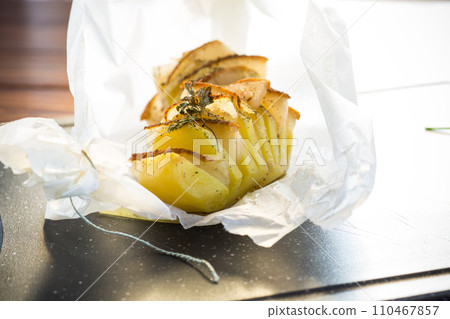 Baked potatoes stuffed with lard in baking paper. Baked potatoes stuffed with lard in baking paper. 110467857