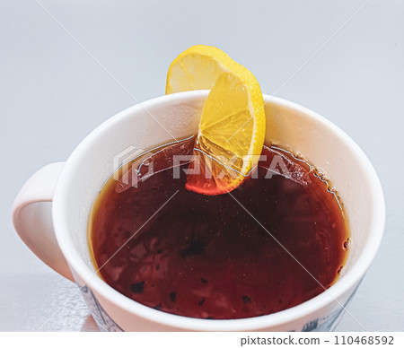 A slice of lemon in a ceramic cup with black tea. 110468592