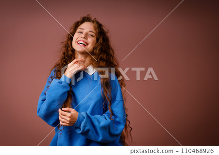 Happy young adult woman wearing winter blue sweater indoors looking at camera with joyful smile Happy young adult woman wearing winter blue sweater indoors looking at camera with joyful smile 110468926