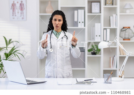 Portrait of female doctor inside clinic office, woman unhappy and upset looking at camera pointing fingers gesture no, working at desk with laptop. Portrait of female doctor inside clinic office, woman unhappy and upset looking at camera pointing fingers gesture no, working at desk with laptop. 110468981