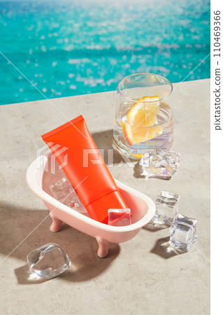 Red tube of sunscreen placed inside a bathtub. A lot of ices scattered on the surface. A cup of detox water featured. The concept of summer holidays, beauty and sunscreen for skin 110469366