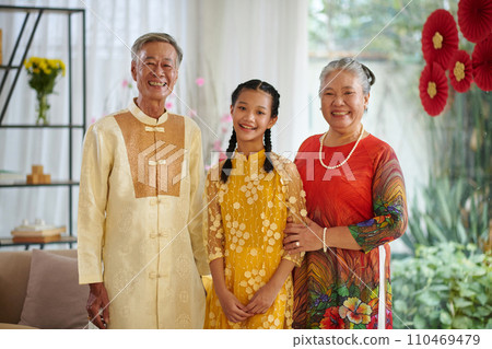 Portrait of happy grandparents and their teenage granddaughter wearing traditional Tet costumes Portrait of happy grandparents and their teenage granddaughter wearing traditional Tet costumes 110469479