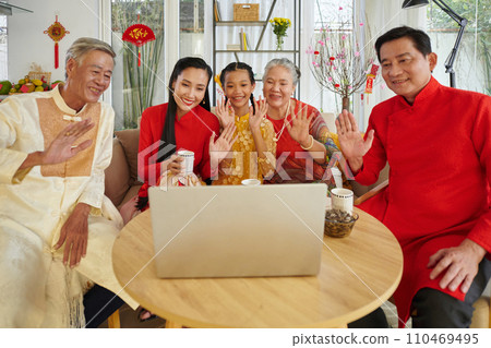 Vietnamese family in traditional costumers video calling relatives to wish happy Lunar New Year Vietnamese family in traditional costumers video calling relatives to wish happy Lunar New Year 110469495