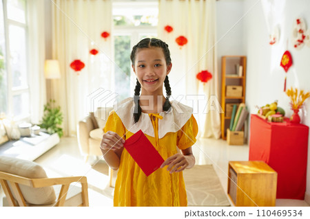 Smiling girl holding red envelope with money as traditional Tet present from family members 110469534
