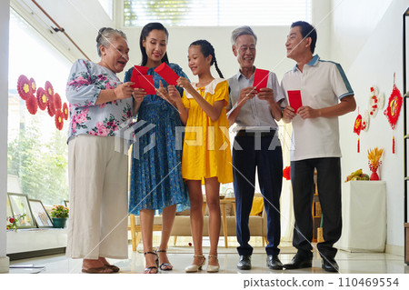 Excited family members exchanging lucky money envelopes when celebrating Tet Excited family members exchanging lucky money envelopes when celebrating Tet 110469554