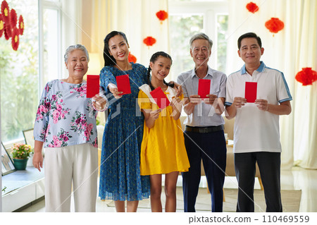 Happy teenage girl with parents and grandparents showing red envelopes with lucky money 110469559