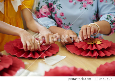 Hands of family members making paper decorations for spring festival 110469592