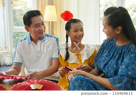 Parents teaching teenage daughter making paper fans for Lunar New Year 110469615