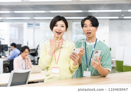 Young staff looking at smartphone in office 110469947