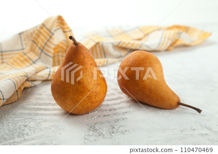 Pears and yellow kitchen towel on white wooden background.. 110470469
