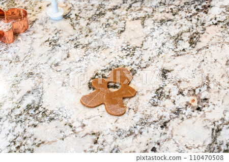 In a contemporary white kitchen, gingerbread cookie dough is skillfully rolled out, setting the stage for a delightful holiday treat. 110470508