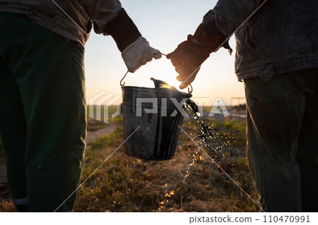 Workers carry a bucket of spilled extracted oil. Discover oil fields. Black gold. 110470991