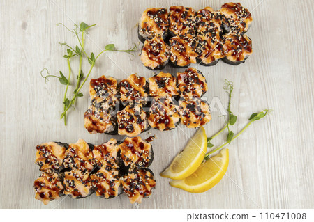Set of baked sushi rolls sprinkled with sesame seeds on a white wooden background. Set of baked sushi rolls sprinkled with sesame seeds on a white wooden background. 110471008