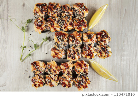 Set of baked sushi rolls sprinkled with sesame seeds on a white wooden background. 110471010