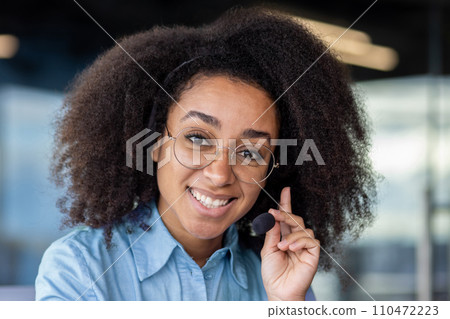 Portrait of joyful successful support worker, woman with headset phone close up smiling and looking at camera, using headset phone for video call online customer consultation Portrait of joyful successful support worker, woman with headset phone close up smiling and looking at camera, using headset phone for video call online customer consultation 110472223