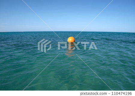 Yellow buoy floating on sea surface as marker for swimming restriction in deep water at tropical resort. Human life safety concept. Yellow buoy floating on sea surface as marker for swimming restriction in deep water at tropical resort. Human life safety concept. 110474196