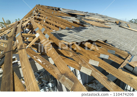 Wind damaged house roof with missing asphalt shingles after hurricane Ian in Florida. Repair of home rooftop concept 110474206