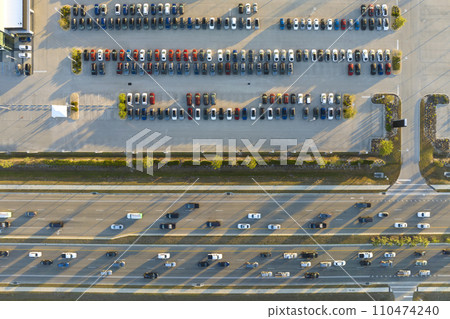 View from above of dealers outdoor parking lot with many brand new cars in stock for sale on highway side. Concept of development of american automotive industry View from above of dealers outdoor parking lot with many brand new cars in stock for sale on highway side. Concept of development of american automotive industry 110474240