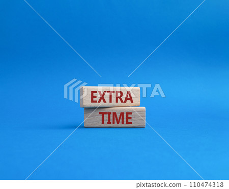 Extra time symbol. Concept word Extra time on wooden blocks. Beautiful blue background. Business and Extra time concept. Copy space 110474318