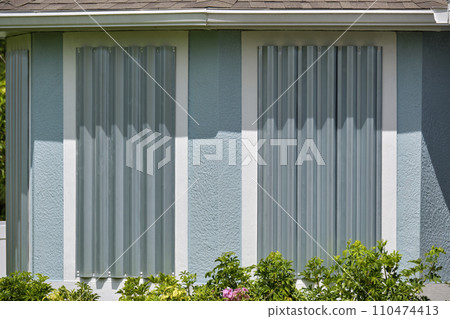 Steel sheets mounted as storm shutters for hurricane protection of house windows. Protective measures before natural disaster in Florida 110474413