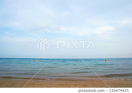 Seascape with surface of blue sea water with small ripple waves crashing on yellow sandy beach. Travel and vacations concept. 110474425