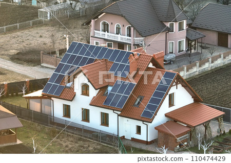 Residential house with rooftop covered with solar photovoltaic panels for producing of clean ecological electrical energy in suburban rural area. Concept of autonomous home Residential house with rooftop covered with solar photovoltaic panels for producing of clean ecological electrical energy in suburban rural area. Concept of autonomous home 110474429