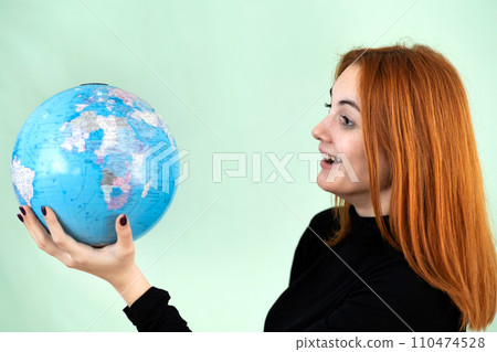 Portrait of a happy young woman holding geographic globe of the world in her hands. Travel destination and planet protection concept. 110474528