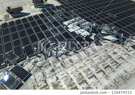Photovoltaic solar panels destroyed by hurricane strong wind mounted on industrial building roof for producing green ecological electricity. Consequences of natural disaster in Florida Photovoltaic solar panels destroyed by hurricane strong wind mounted on industrial building roof for producing green ecological electricity. Consequences of natural disaster in Florida 110474533