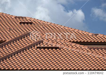 House rooftop covered with yellow ceramic shingles. Tiled covering of residential apartment building 110474642