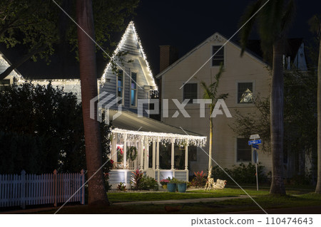 House front yard with big porch brightly illuminated with Christmas decorations. Outside decor of Florida family home for winter holidays 110474643