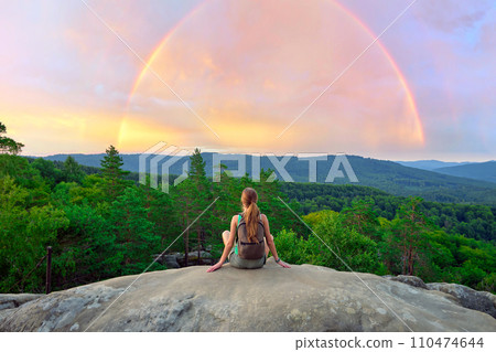Hiker woman resting on rocky mountain top enjoying morning nature during her travel on wilderness trail. Lonely female traveler traversing high hilltop route. Hiker woman resting on rocky mountain top enjoying morning nature during her travel on wilderness trail. Lonely female traveler traversing high hilltop route. 110474644