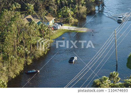 Flooded road in Florida after heavy hurricane rainfall. Aerial view of evacuating cars and surrounded with water houses in suburban residential area Flooded road in Florida after heavy hurricane rainfall. Aerial view of evacuating cars and surrounded with water houses in suburban residential area 110474693