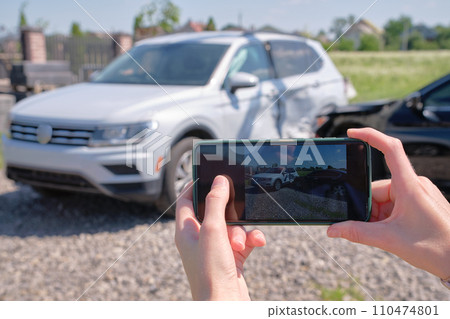 Female driver hands photographing on sellphone camera wrecked vehicles on street side for insurance service after car accident. Road safety concept 110474801