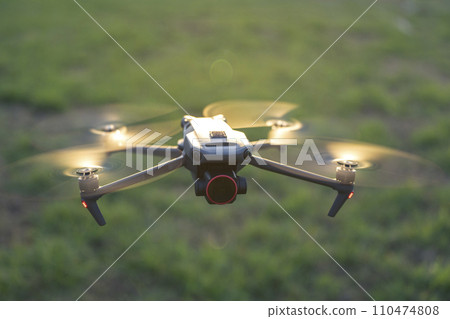 Drone quadcopter with digital camera and fast rotating propellers flying taking video and pictures 110474808