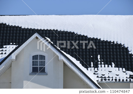 Closeup of house roof top covered with snow in cold winter. Tiled covering of building in wintertime weather 110474847