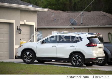 Car parked in front of wide garage double door on concrete driveway of new modern American house 110474996
