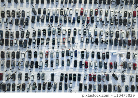 Aerial view of vehicle open market lot with many cars for sale parked and people customers walking in winter 110475029