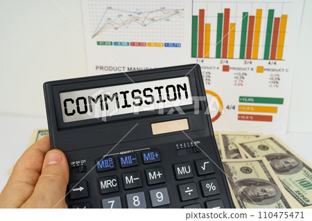 On the table there are financial reports, dollars, in the hands of a calculator with the inscription - COMMISSION On the table there are financial reports, dollars, in the hands of a calculator with the inscription - COMMISSION 110475471
